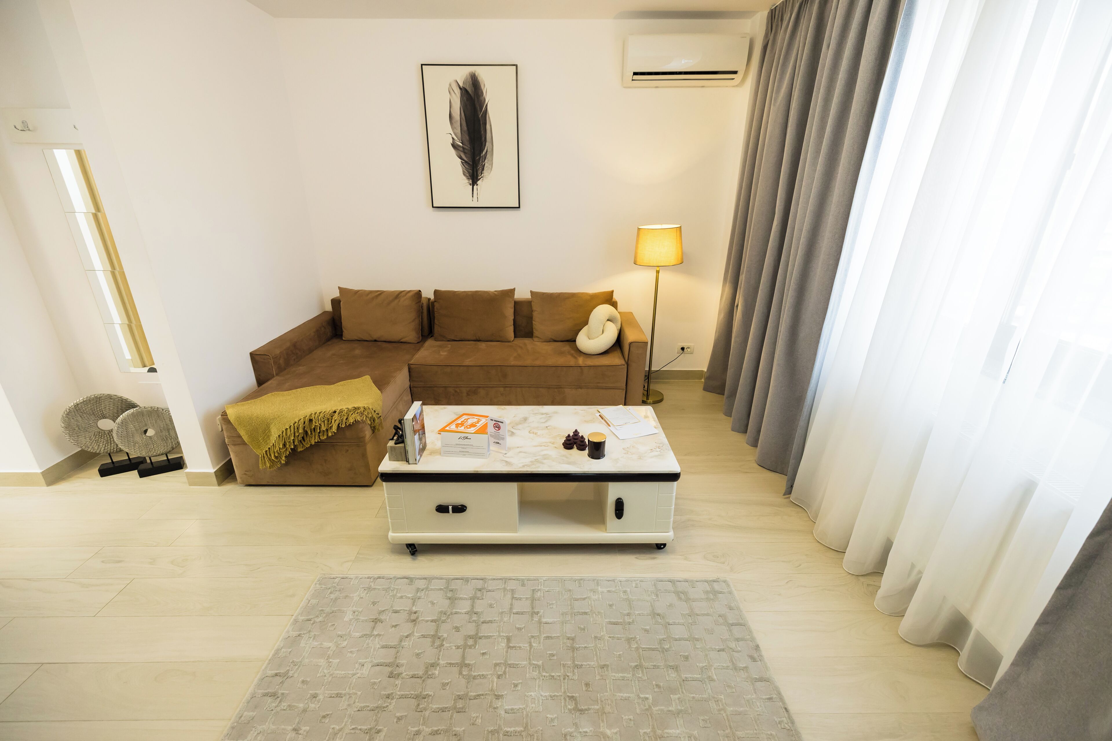 A living room with a brown sofa, a white coffee table, and a lamp.