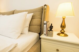 A neatly made bed with white linens, a bedside table with a lamp, and a book titled "Living in Bali".