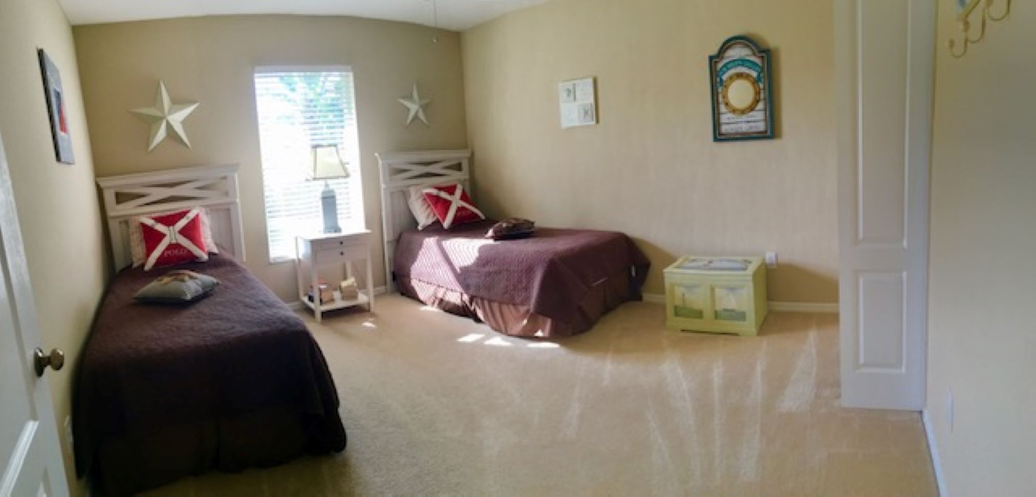 A bedroom with two beds, a nightstand, a lamp, and a small cabinet.
