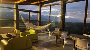 A spacious balcony with a hammock, yellow and white furniture, and a view of mountains. - Sierra Morena Eco-Hotel (Filandia)