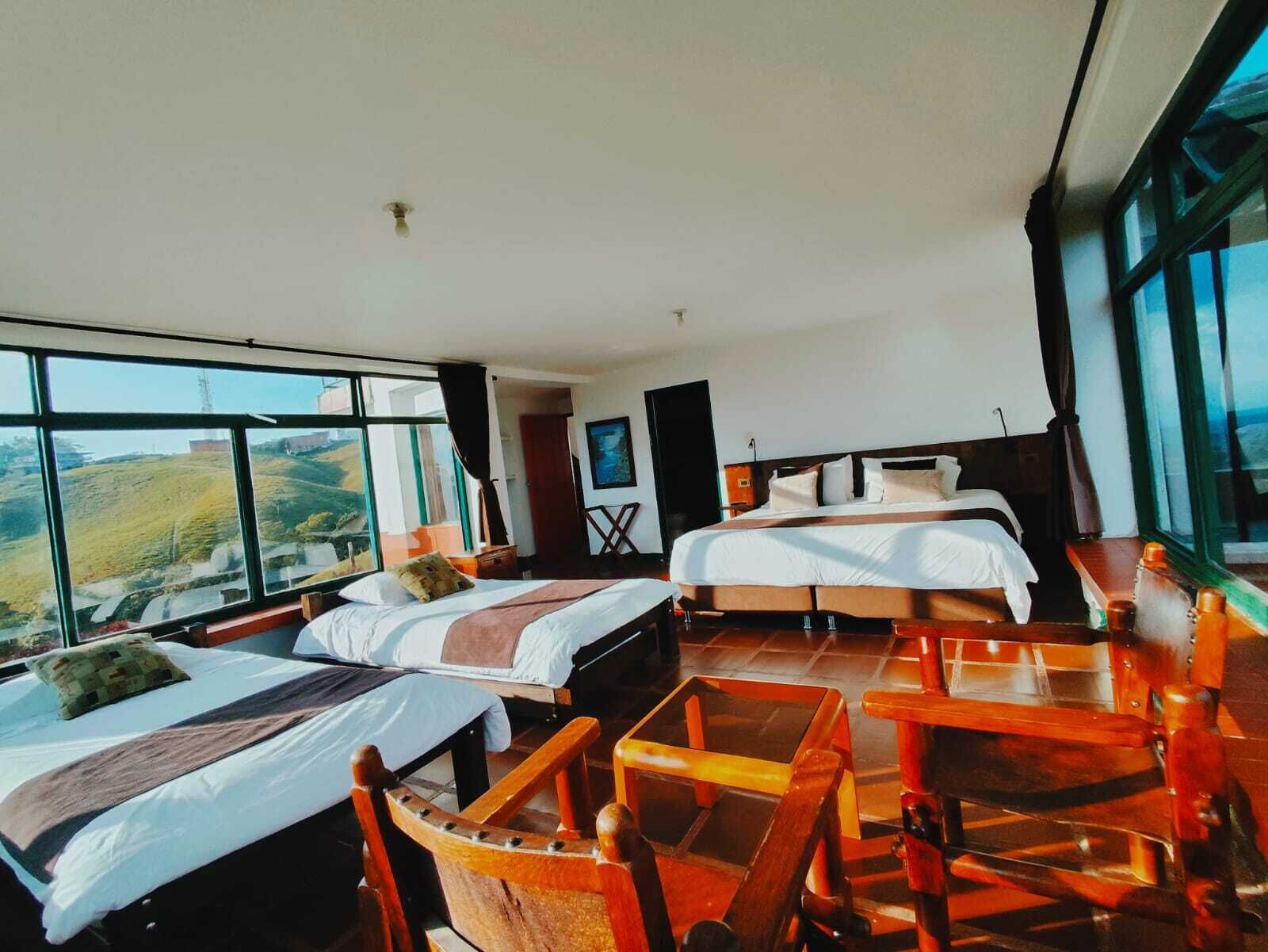 A hotel room with two beds, large windows, and a view of the countryside.