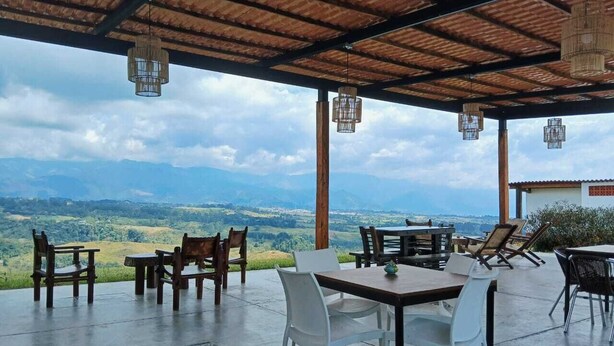 An outdoor patio with tables and chairs, overlooking a mountainous landscape. - Sierra Morena Eco-Hotel (Filandia)