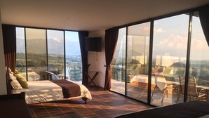 A spacious bedroom with two beds, a TV, and a balcony with a scenic view. - Sierra Morena Eco-Hotel (Filandia)