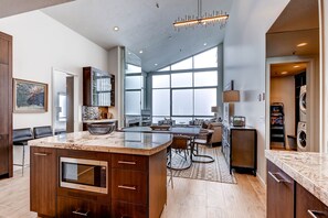 A modern kitchen with a large island, built-in appliances, and a dining area with a view.
