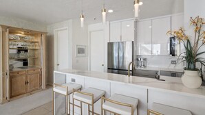A modern kitchen with a central island, bar stools, a stainless steel refrigerator, and pendant lighting. - Comfort, Convenience, and Modern Amenities at this Ski in/Ski Out Condominium (Alta)