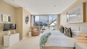 A modern bedroom with a large bed, a TV, a chair, and a balcony with a mountain view. - Comfort, Convenience, and Modern Amenities at this Ski in/Ski Out Condominium (Alta)