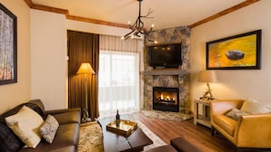 A cozy living room with a stone fireplace, a television mounted above it, and a comfortable seating area with a sofa and armchairs. - Two Bedroom Luxury Villa, Park City, Utah (1920607) (Park City)