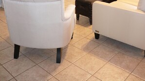Un salon avec un canapé blanc, un fauteuil blanc, une table basse et un meuble blanc avec des étagères.