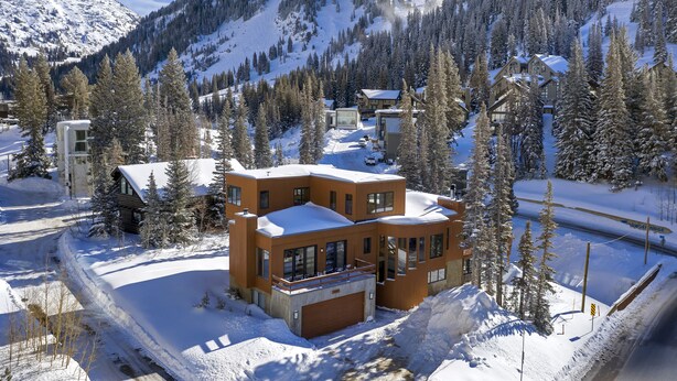 A modern multi-story lodge with a snow-covered roof, surrounded by a forest and mountains. - Luxury Alta Utah Home with Hot Tub, Pool Table, Game Room and Chef's Kitchen (Alta)