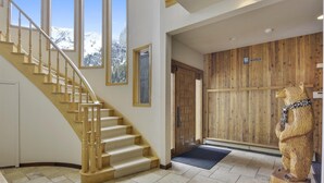 A staircase with wooden balusters and beige carpeted steps leading to a door with a wooden panel wall. - Luxury Alta Utah Home with Hot Tub, Pool Table, Game Room and Chef's Kitchen (Alta)