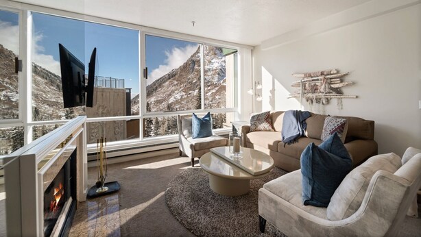 A spacious living room with a large window offering a mountain view, a fireplace, and a cozy seating area. - Ski in/Ski Out to Snowbird in this Delightful Condominium with Fireplace (Alta)
