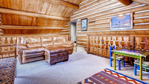 A log cabin interior with a leather sofa, a wooden dining table with chairs, and a framed picture on the wall. - Gorgeous Log Cabin in Alta with Outdoor Hot Tub and Wood Burning Fireplace (Alta)