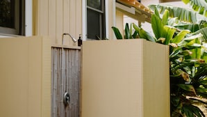 A house with a wooden exterior, a window with a checkered curtain, and a small outdoor area with a bamboo fence and a plant. - Hawaiian Charm..Just Steps From The Ocean..On Kauai's Sunny W Side * TVNC4216 (Kekaha)