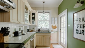 A kitchen with white cabinets, a black stove, and a window with a view of trees. - Hawaiian Charm..Just Steps From The Ocean..On Kauai's Sunny W Side * TVNC4216 (Kekaha)