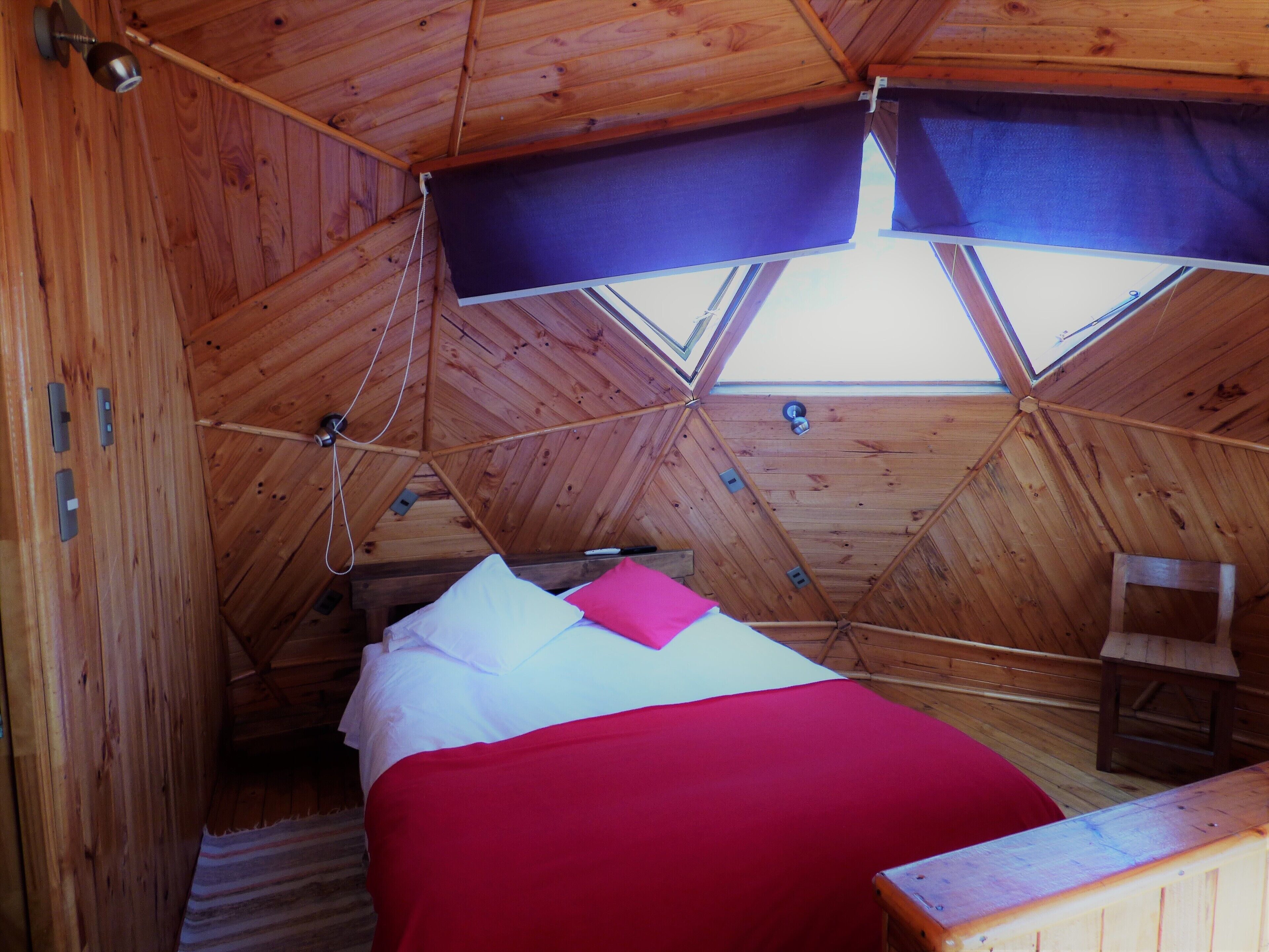 A cozy attic bedroom with a bed, a chair, and a skylight.