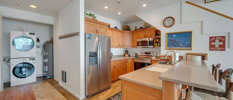 A modern kitchen with stainless steel appliances, wooden cabinets, and a large island.