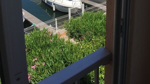 A marina with several boats docked, a building with arched windows in the background, and a balcony with greenery. - Charming, colourful and functional T2 apartment 200m from the beach free, enclosed parking (Sète)