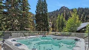 A hot tub with a glass barrier, surrounded by trees and a mountain view. - Luxury and Location in this Incredible Home with Brand New Outdoor Hot Tub and 2 Car Garage! (Alta)