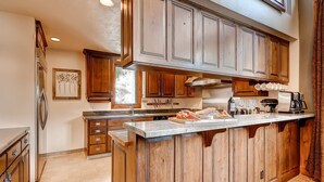 A kitchen with wooden cabinets, a granite countertop, and a built-in island. - Luxury and Location in this Incredible Home with Brand New Outdoor Hot Tub and 2 Car Garage! (Alta)