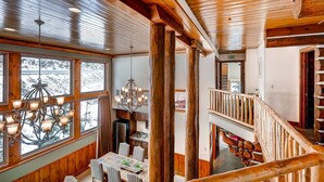 A multi-level wooden interior with a dining area, chandelier, and a staircase. - Luxury and Location in this Incredible Home with Brand New Outdoor Hot Tub and 2 Car Garage! (Alta)