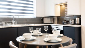 Una cocina moderna con una mesa de comedor dispuesta para cuatro, con cuencos blancos y copas de vino.