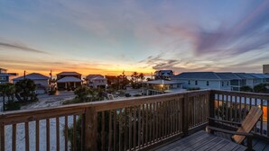 A beachfront property with a wooden deck, multiple houses, and a sunset view. - Beach Side “Crabby Paddy", Luxury family retreat 6br 4+ bath w pool+hot tub (Panama City Beach)