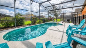 Une piscine entourée d’une structure en verre, avec des chaises bleues et un transat.