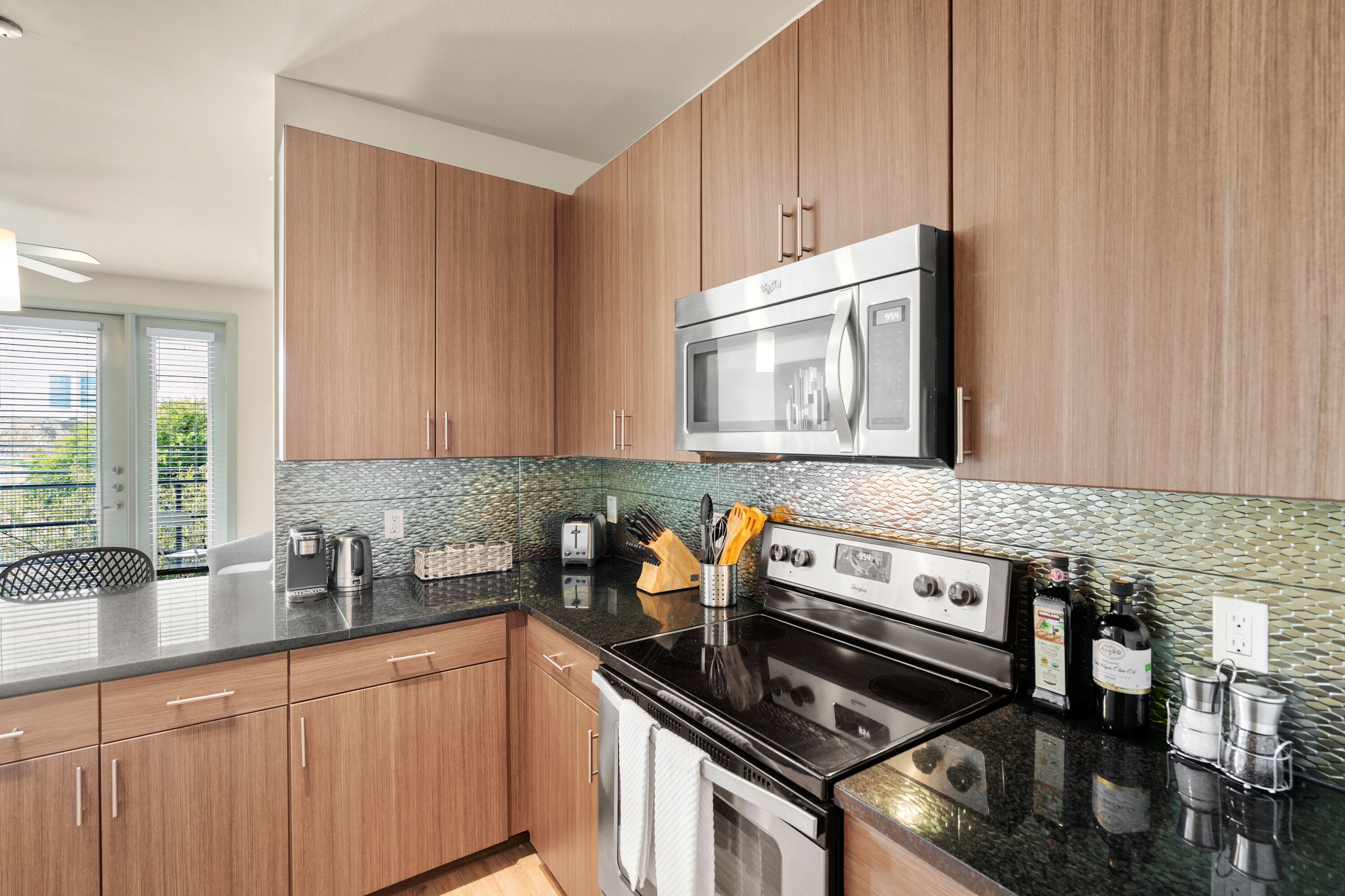 A modern kitchen with wooden cabinets, a stainless steel microwave, and a black stove.