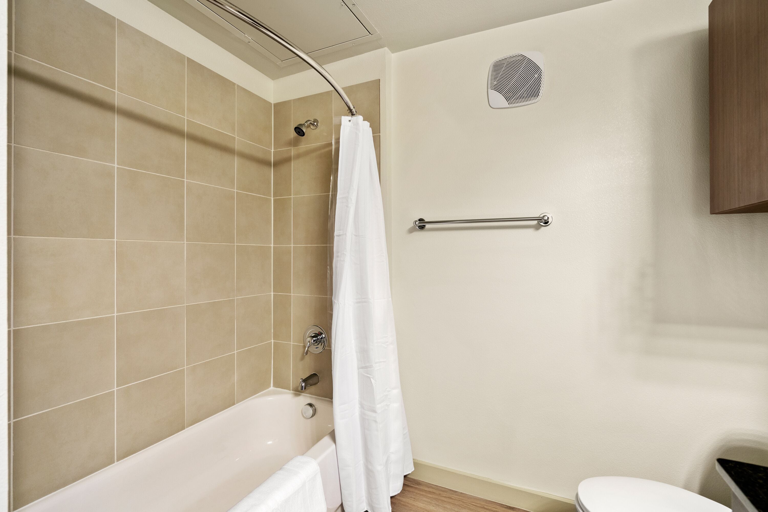 Un baño con bañera, ducha, inodoro y un perchero para toallas.