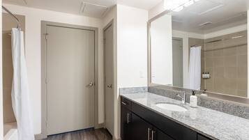 A modern bathroom with a large mirror, a sink, and dark cabinets.