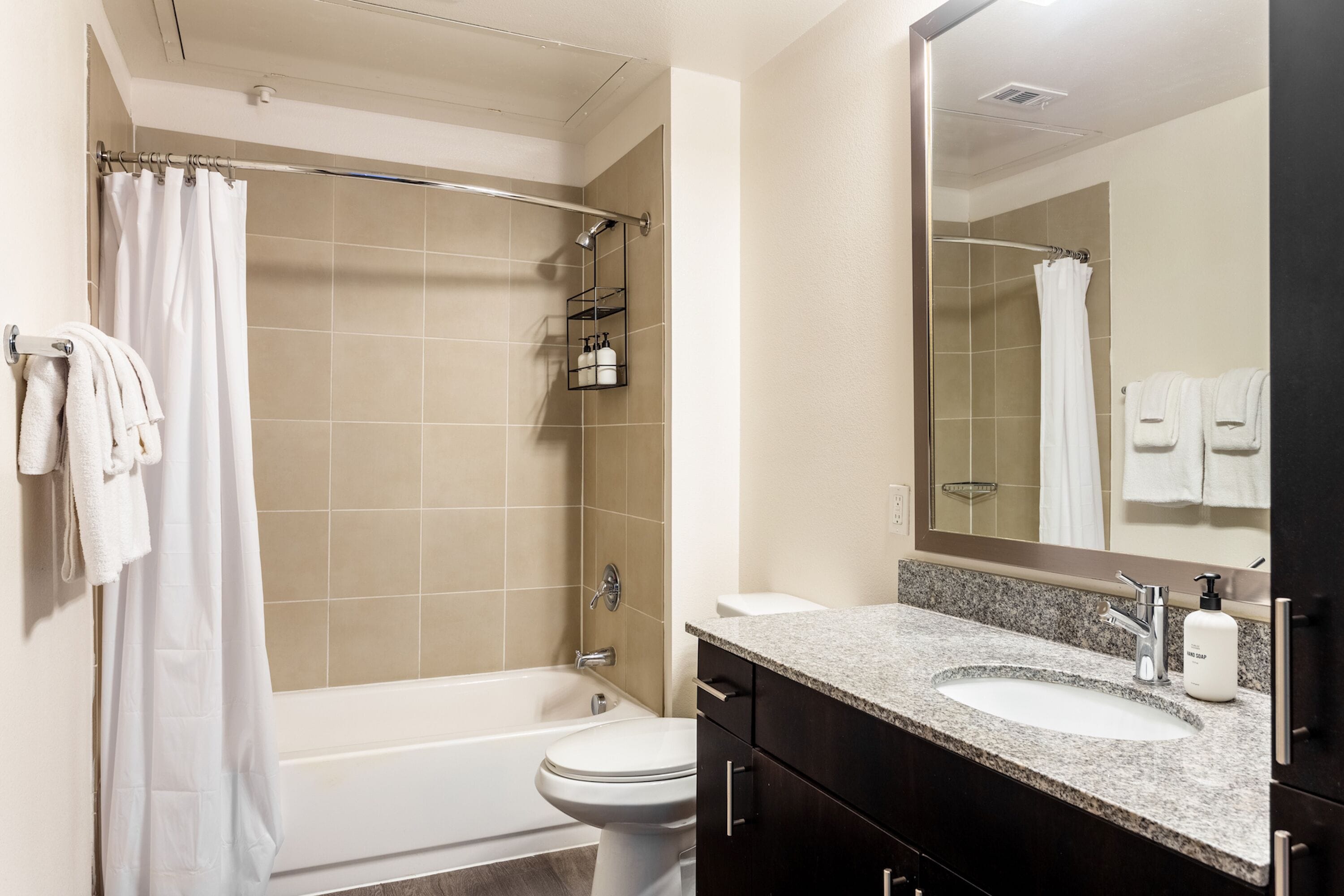 Une salle de bain équipée d’une baignoire, de toilettes, d’un lavabo et d’un grand miroir.