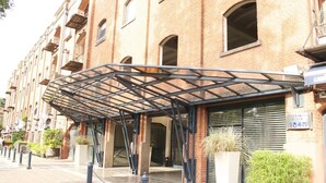 A hotel entrance with a covered walkway, brick facade, and a number plaque. - Exclusive apartment of 120 m2 overlooking the river and free parking (Puerto Madero)