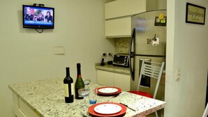 A small kitchen with a TV, a microwave, and a refrigerator. There are two red plates and a bottle on the counter. - Exclusive apartment of 120 m2 overlooking the river and free parking (Puerto Madero)