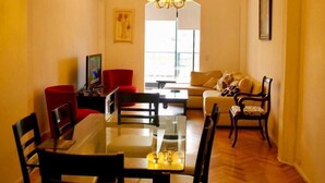 A dining area with a glass table, wooden chairs, and a chandelier. - Exclusive apartment of 120 m2 overlooking the river and free parking (Puerto Madero)