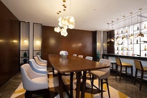 Un comedor moderno con una larga mesa de madera, sillas blancas y un candelabro decorativo colgante.