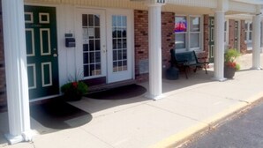 A building with a green door labeled "OFFICE" and a bench outside. - Walton Inn (Willard)