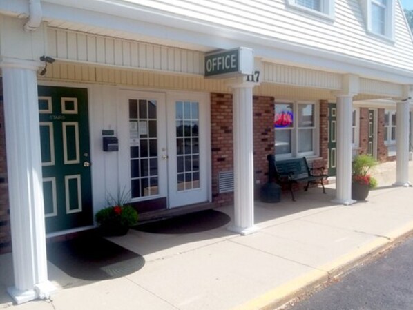 A building with a green door labeled "OFFICE" and a bench outside.