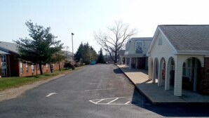A street with a row of brick buildings on one side and a white building with arched windows on the other. - Walton Inn (Willard)