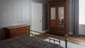 A bedroom with a bed, a wooden dresser, a wardrobe, and a door. - La Bicyclette Bleue (Montmorillon)