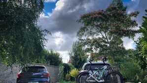 A car parked in a driveway with a bicycle mounted on the back. - La Bicyclette Bleue (Montmorillon)