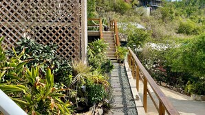 Un sendero que conduce a una escalera de madera con vistas a una colina y un edificio al fondo.