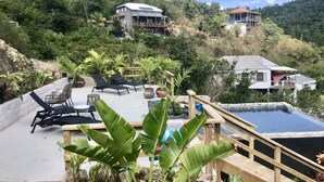 Una propiedad en la ladera con piscina, sillas de descanso y terraza de madera.