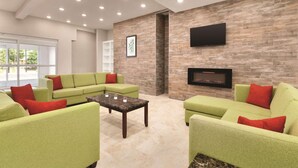 A modern living room with green sofas, a coffee table, a fireplace, and a mounted TV. - Country Inn & Suites by Radisson, Greensboro, NC (Greensboro)