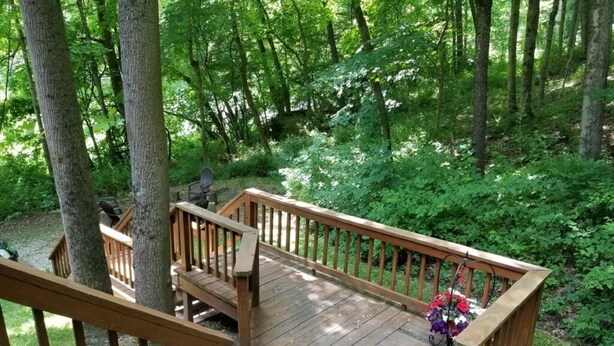 A wooden deck with a railing, surrounded by trees and greenery. - Vacation cabin in the beautiful Hocking Hills (Sugar Grove)