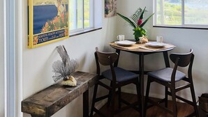 Un coin repas comprenant une table ronde, quatre chaises, un banc et deux affiches accrochées au mur.