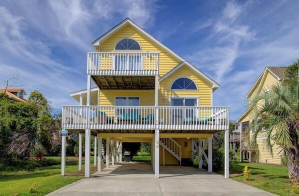A two-story yellow house with a balcony and a covered entryway. - "Always Sunny" Beautifully Remodeled Home, Quick Walk to Beach (Surf City)