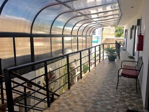 A covered outdoor area with a metal railing, stone flooring, and potted plants. - Hotel La Casa del Capi   (Isla Holbox)