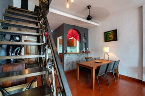 Staircase leads to an upper level, with a dining area and kitchen visible through an archway.