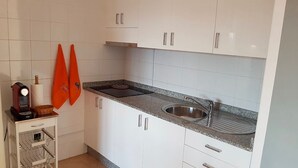 A kitchen with white cabinets, a granite countertop, a stainless steel sink, and a coffee machine.