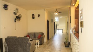 A spacious living area with a sofa set, a small table, and a potted plant. - Sunset Inn Guest House (Monrovia)